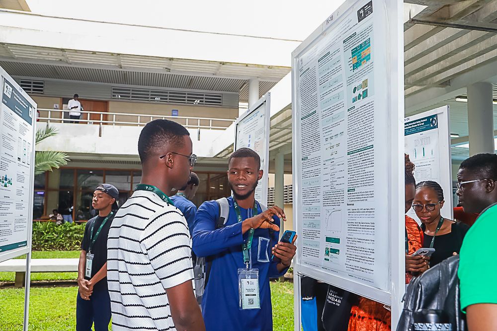 Participants exchanging ideas beside a research poster at Indaba